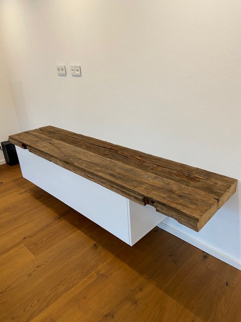 Weißes, an der Wand hängendes TV-Möbel mit einer Platte aus alten Eichenbohlen